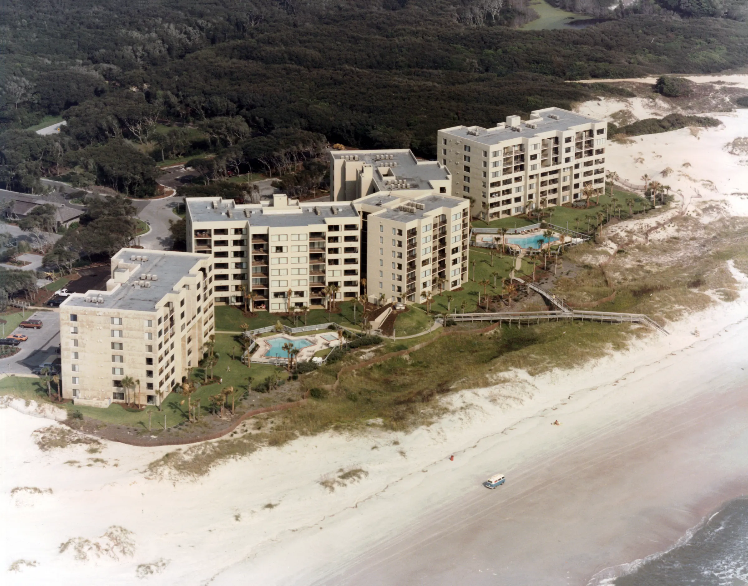 Archival aerial of Amelia Surf & Racquet Club’s three oceanfront buildings, with a Volkswagen bus driving on the beach